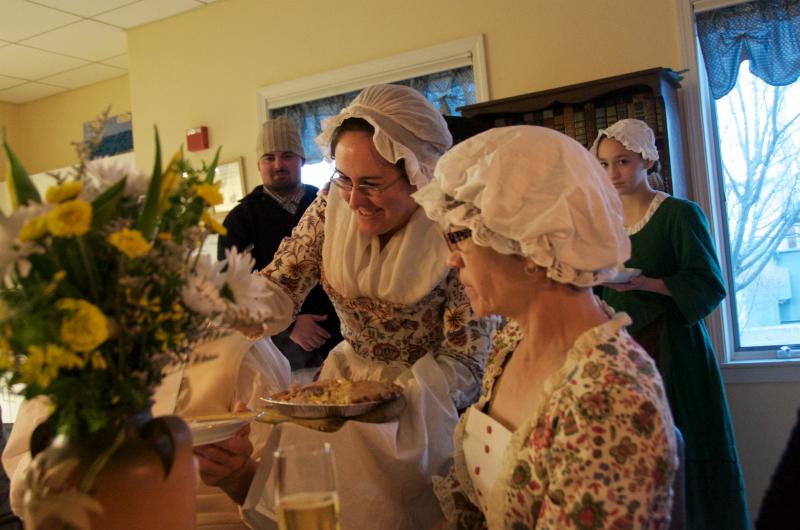 A member of the militia serves up onion pie, which turned out to be a hit of the evening. BY GEORGIA SPARLING